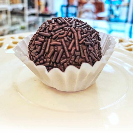 brigadeiro em prato em branco com loja no fundo